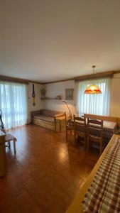 uma sala de estar com bancos, uma mesa e janelas em Trilocale accogliente con camino a pochi minuti da Madonna di Campiglio em Spiazzo