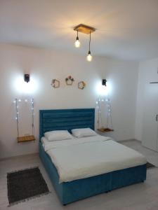 ein blaues Bett in einem weißen Zimmer mit zwei Lichtern in der Unterkunft Belleview North Studio in Sinaia