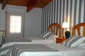 two beds in a room with striped walls at Hostal Cervantes in Daganzo de Arriba