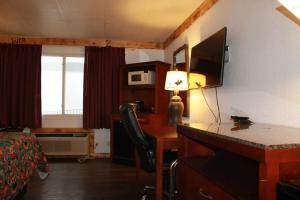 ein Hotelzimmer mit einem Schreibtisch, einem Bett und einem TV in der Unterkunft Wyatt Earp Hotel in Dodge City