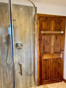 a shower in a bathroom with a wooden door at Claire's Townhouse, Aberdeenshire, 3 bedrooms in Oldmeldrum