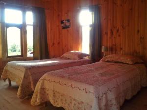 two beds in a room with wooden walls and windows at Casa Alma in Vicuña