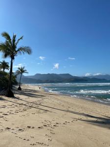 a beach with palm trees and the ocean at Flat 1 Dorm. Maresias Praia&Lazer& Ar&Piscina F3 in São Sebastião