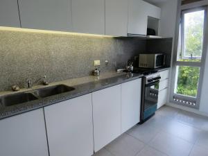 a kitchen with white cabinets and a sink and a window at Espectacular Departamento Playa Grande/Golf Club Cochera Vista Moderno in Mar del Plata