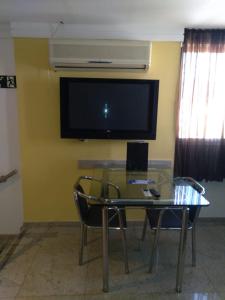 uma sala de estar com uma mesa de vidro e uma televisão de ecrã plano em Flash Motel (Adult Only) em São Vicente
