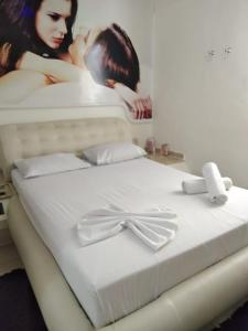 Flash Motel (Adult Only) في ساو فيسينتي: سرير أبيض عليه صورة امرأة +18 صورة