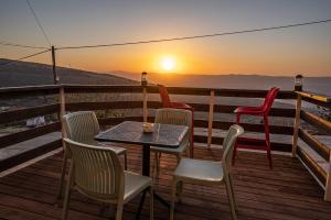 a table and chairs on a deck with the sunset at Sunset B&B in Ein Kinya