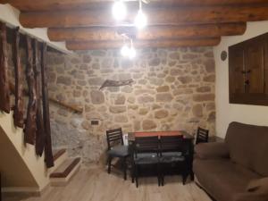 ein Wohnzimmer mit einem Tisch, Stühlen und einer Steinmauer in der Unterkunft Casa Rural El Secreto del Castillo in Mora de Rubielos