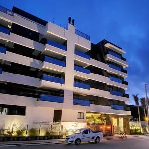 a white car parked in front of a large building at Apartamento 2 quartos home club na praia de palmas in Governador Celso Ramos