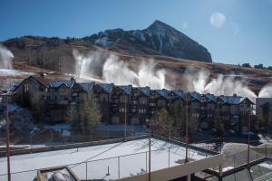 a building with geysers in front of a mountain at The Plaza Condominiums by Crested Butte Mountain Resort in Mount Crested Butte