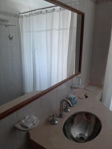 W łazience znajduje się umywalka z lustrem i prysznic. w obiekcie LOWCOST MADRYN w mieście Puerto Madryn