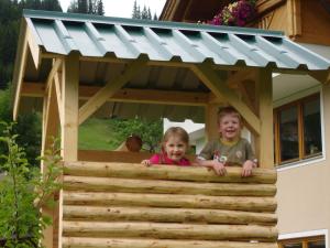 duas crianças a olhar para fora de uma casa de brincar em Haus Gföller em Niederau