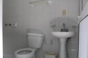 a white bathroom with a toilet and a sink at Hotel Palmarito in Puerto Escondido