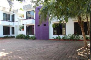 un bâtiment violet avec un palmier devant lui dans l'établissement Hotel Palmarito, à Puerto Escondido