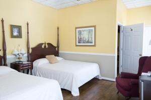a bedroom with two beds and a red chair at Inn at the Olde Silk Mill in Fredericksburg