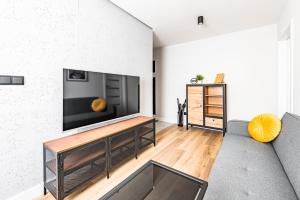 een woonkamer met een flatscreen-tv aan de muur bij Apartament Frida Katowice Ligota in Katowice