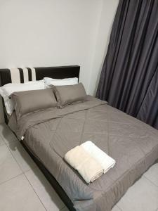 duże łóżko z szarym kocem i poduszkami w obiekcie Meritus Apartment w mieście Perai