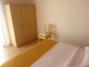 een slaapkamer met een bed, een stoel en een kast bij Apartment Drago - 50 m from sea in Betina