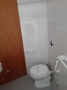 a bathroom with a white toilet and a brown door at LOWCOST MADRYN in Puerto Madryn
