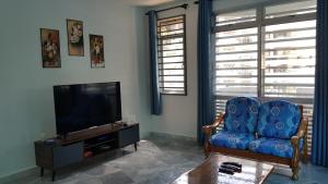 ein Wohnzimmer mit einem blauen Stuhl und einem TV in der Unterkunft PD Batu 9 Cocobay apartment with family in Kampong Tanah Merah