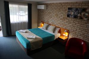 ein Schlafzimmer mit einem Bett und einer Ziegelwand in der Unterkunft Kilcoy Gardens Motel in Kilcoy
