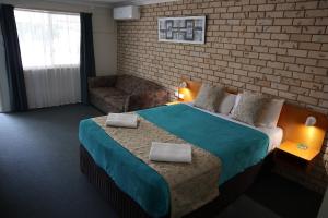 a hotel room with a bed, table and a lamp at Kilcoy Gardens Motel in Kilcoy