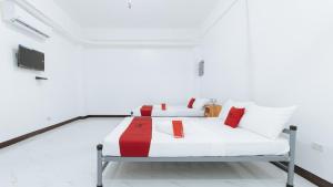 Dieses weiße Zimmer verfügt über 2 Betten mit roten und weißen Kissen. in der Unterkunft RedDoorz @ Catalina Pension House in Balingasag