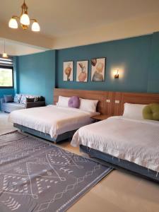 a bedroom with two beds and a blue wall at 910 Hostel 城南館-自助入住 in Yuli