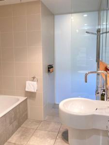 Luxury Hobart Waterfront Apartment with views! في هوبارت: حمام مع حوض ومغسلة ودش