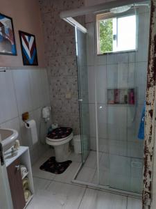 uma casa de banho com uma cabina de duche em vidro e um WC. em Casa perto do centro em Garopaba