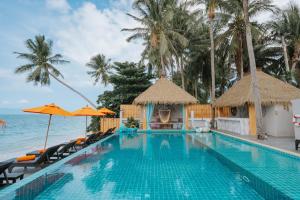 einen Pool mit Stühlen und Sonnenschirmen am Meer in der Unterkunft Mimosa Resort & Spa in Mae Nam