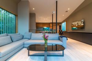 a living room with a blue couch and a glass table at Boheme by H2 Life in Kutchan