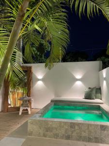 a pool in a backyard with a bed and a palm tree at Pousada Vila Piola in Guarda do Embaú