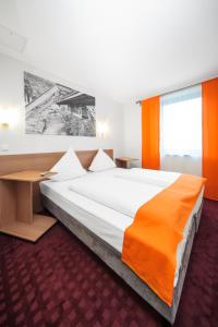 a bedroom with a large bed with an orange blanket at McDreams Hotel Wuppertal City in Wuppertal