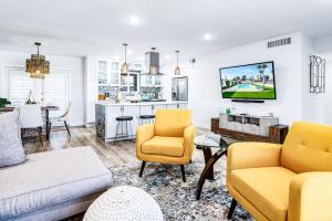 a living room with yellow chairs and a kitchen at PD Retreat Permit# STR2022-0253 in Palm Desert