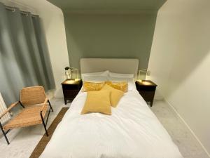 Una cama con almohadas amarillas y una silla en una habitación en Station Rooms, en Winchester