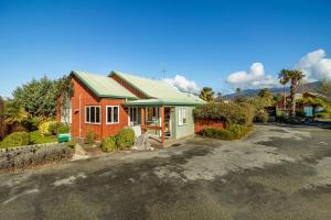 une maison rouge avec un toit vert dans une rue dans l'établissement Anatoki Lodge Motel, à Takaka