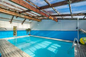 an indoor swimming pool with blue walls and a wooden ceiling at Anatoki Lodge Motel in Takaka