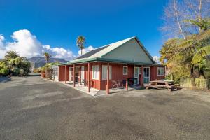 a red and green building with a picnic table at Anatoki Lodge Motel in Takaka