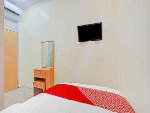 una camera con letto e TV a parete di OYO 90804 Oma Uti Homestay Syariah a Yogyakarta