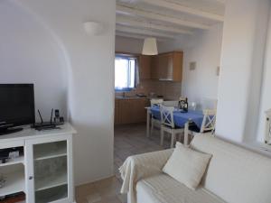 a living room with a white couch and a kitchen at S & K Maisonnettes in Pounda