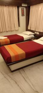 two beds sitting in a room with at Hotel Aston in Kolkata