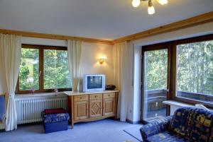 a living room with a tv on a dresser with windows at Bergführer-Hüsle in Mittelberg