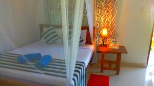a bedroom with a bed and a table with a lamp at Nice View Lodge in Sigiriya