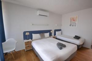 1 dormitorio pequeño con 2 camas y 1 silla en South Seas Motel, en Merimbula