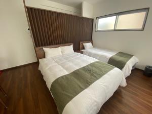 two beds in a room with wood floors and a window at VILLA COZYSTAY92 宮古島 in Miyako Island