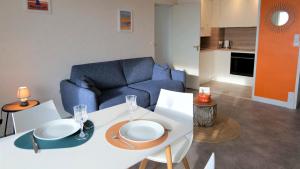 拉波勒Lutin Vue Baie La Baule - Appartement T2 design et connecté的客厅里有一张桌子和一张蓝色沙发