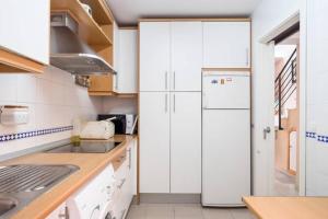 uma cozinha com armários brancos e um frigorífico branco em Dorado Playa em Huelva