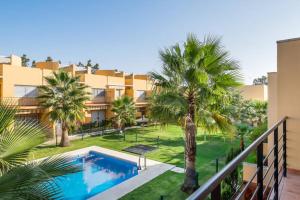a swimming pool with palm trees in front of a building at Dorado Playa in Isla Cristina