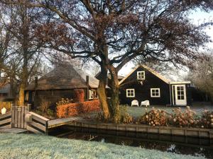 a black house with a tree in the yard at Logement Bilderdam in Leimuiden